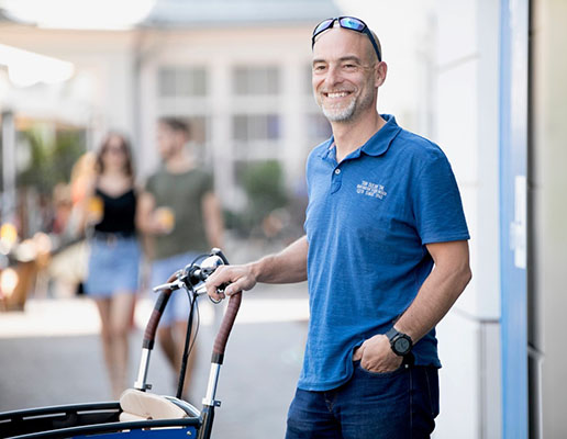 Ein lächelnder Mann in blauem T-Shirt.